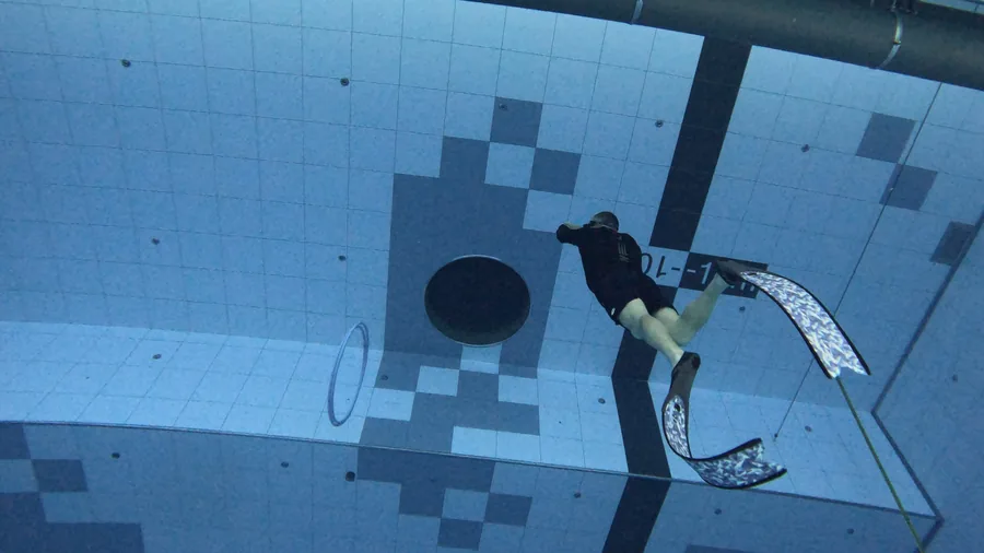 Freediver descending in a deep indoor pool
