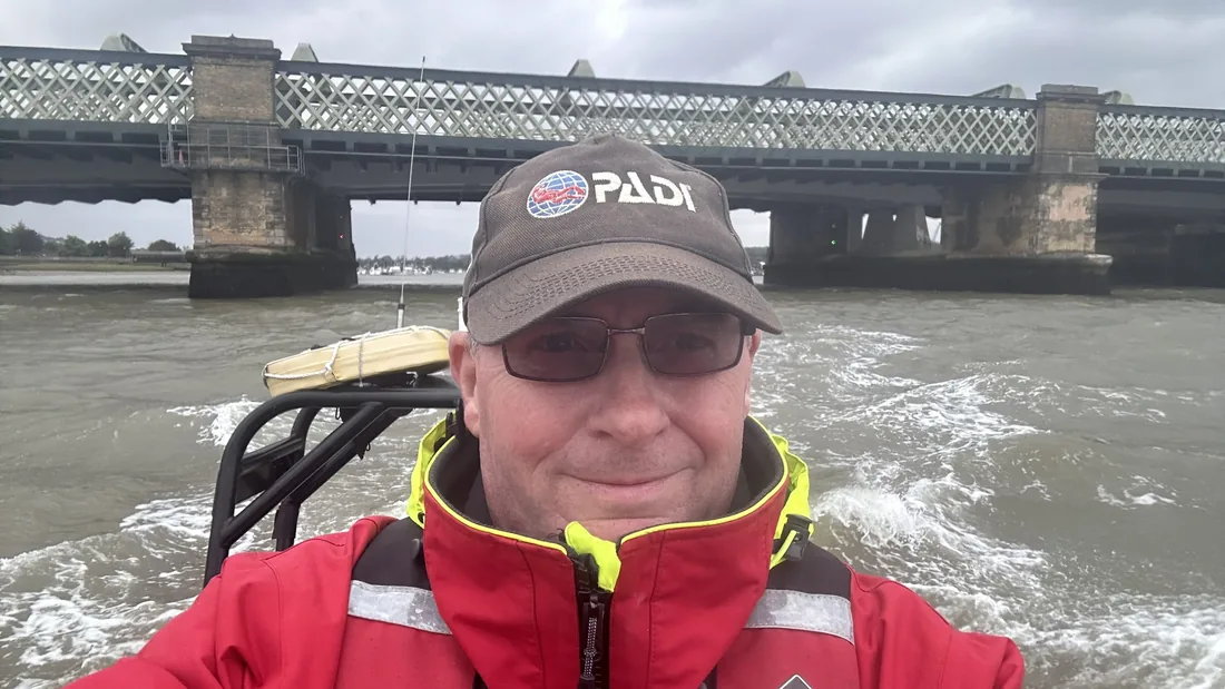 Andrew Grundy wearing a PADI cap on a dive boat