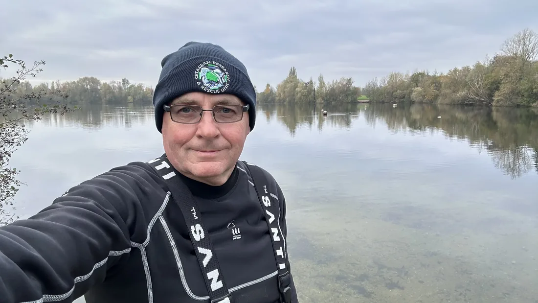 Andrew Grundy beside a lake wearing rescue diver clothing